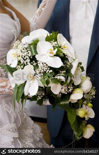 Bride hold the bouquet from orchids and stand near the groom