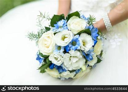 bride holding a bouquet with blue flowers in her hands