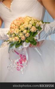 Bride holding wedding bouquet. Wedding bouquet with roses on a wooden bench