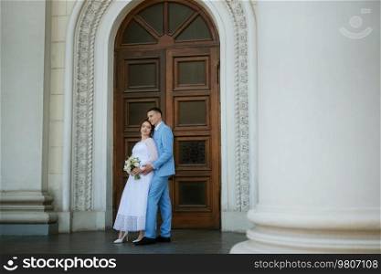 bride in a light wedding dress with a bouquet next to the groom in a blue suit