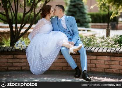 bride in a light wedding dress with a bouquet next to the groom in a blue suit