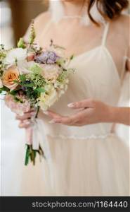Bride in a wedding dress holding a wedding bouquet in her hands. Bride in a wedding dress holding a wedding bouquet in her hands close-up