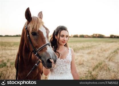 bride in a white dress next to a brown horse in the village