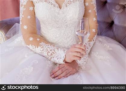 bride in a white wedding dress holds a glass of wine in her hand. the bride in a white wedding dress holds a glass of wine in her hand