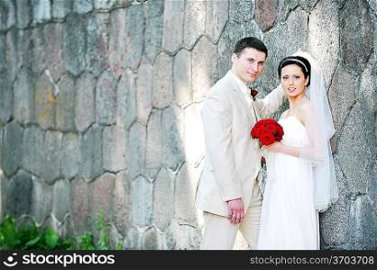 bride in white dress and groom near old wall