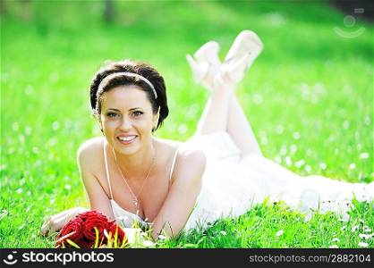 bride in white dress lying down in grass.