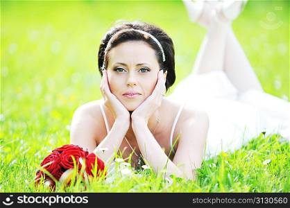 bride in white dress lying down in grass.
