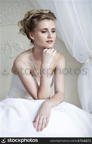 Bride is sitting on bed in hotel room