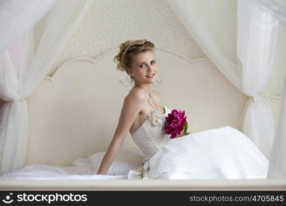 Bride is sitting on bed in hotel room