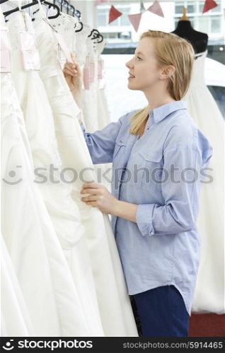 Bride Looking At Price Tag On Wedding Dress In Bridal Boutique