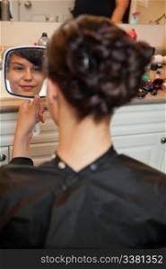 Bride looking in mirror at hair style before wedding
