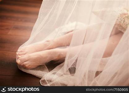 Bride morning preparation. Bride legs in white veil on wooden floor. Bride morning preparation. Bride legs in white veil on wooden floor.