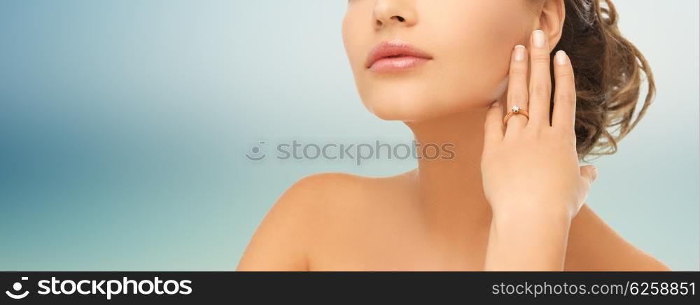 bride, people, jewelry and wedding concept - close up of beautiful woman with diamond engagement ring over blue background