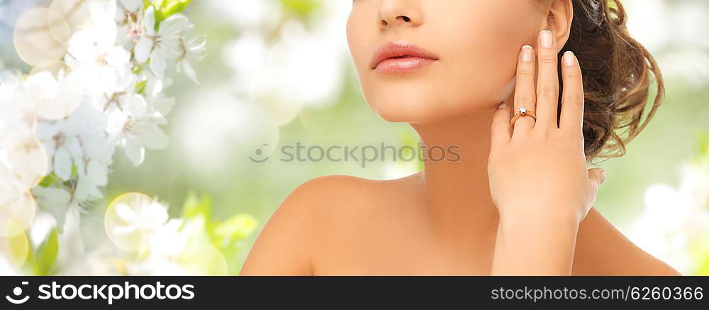 bride, people, jewelry and wedding concept - close up of beautiful woman with diamond engagement ring over summer garden and cherry blossom background