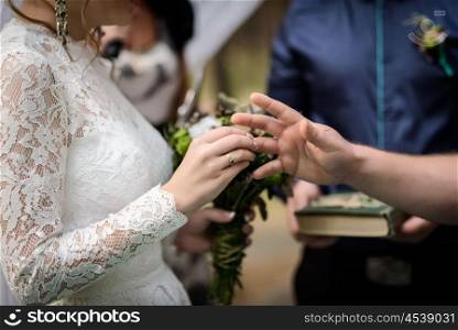 bride puts wedding ring on groom finger