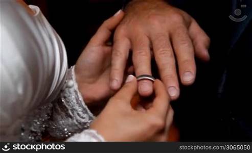 Bride putting a wedding ring on groom&acute;s finger