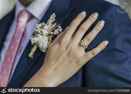 Bride?s hand and rings on groom?s outfit