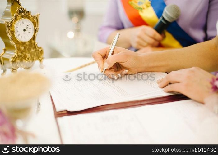 bride signs marriage certificate with a pen