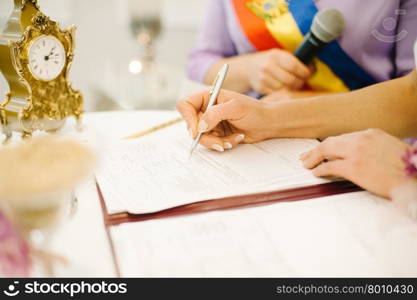 bride signs marriage certificate with a pen