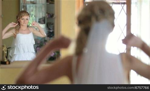 Bride sits before a mirror in the morning of the wedding day