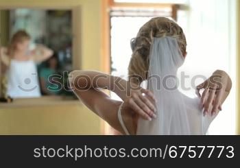 Bride sits before a mirror in the morning of the wedding day