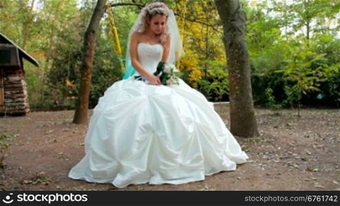 Bride sits on a swing in the autumn park