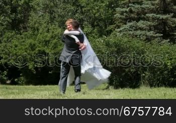 bride spinning groom holding her in his arms in the park