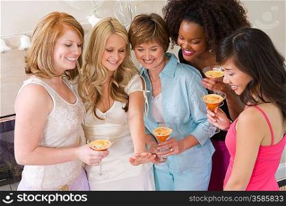Bride standing together with friends watching her engagement ring