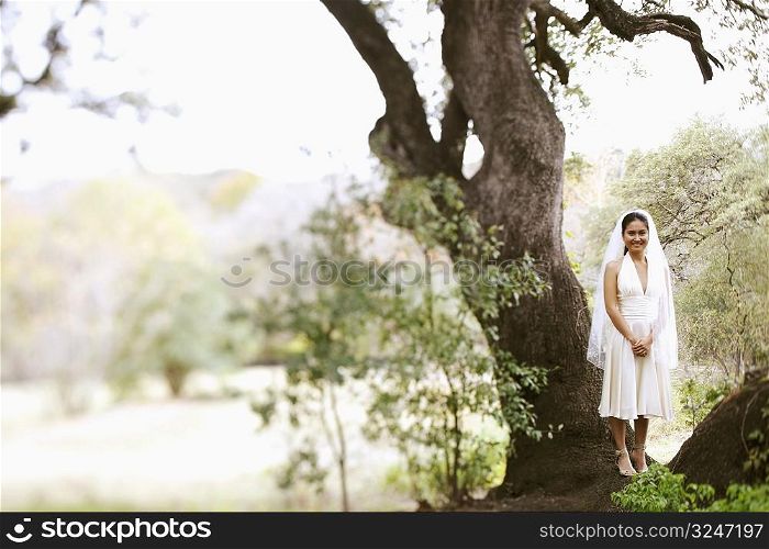 Bride standing under a tree and smiling