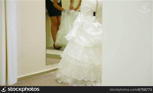 Bride trying on wedding dress in fitting room