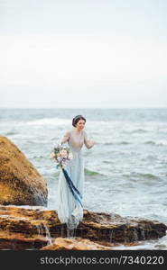 bride with a bouquet of flowers on the beach near the water