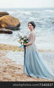 bride with a bouquet of flowers on the beach near the water