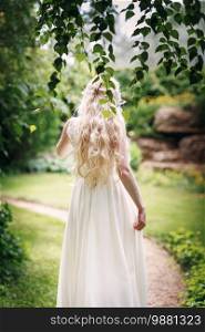 Bride with long fair hair from back in the garden