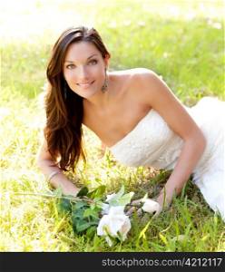 bride woman lying in park grass with white rose