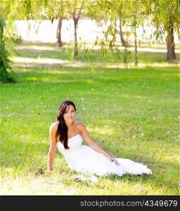 bride woman sitting in park grass with white rose