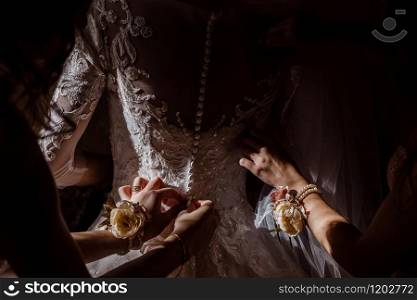 Bridesmaid helping bride fasten corset and getting her dress, preparing bride in morning for the wedding day. Bridesmaid helping bride fasten corset and getting her dress, preparing bride in morning for the wedding day.