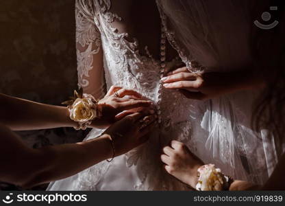 Bridesmaid helping bride fasten corset and getting her dress, preparing bride in morning for the wedding day. Bridesmaid helping bride fasten corset and getting her dress, preparing bride in morning for the wedding day.