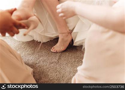 bridesmaids help her to put on shoe shoes on heels. wedding morning preparation. High quality photo.. bridesmaids help her to put on shoe shoes on heels. wedding morning preparation. High quality photo