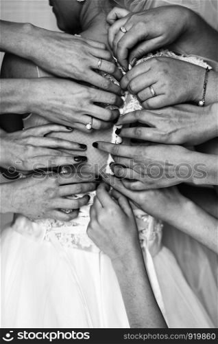 Bridesmaids preparing bride for the wedding day. Hands bridesmaids helps fasten a wedding dress the bride before the ceremony close up.. Best wedding morning. Wedding concept. black white photo