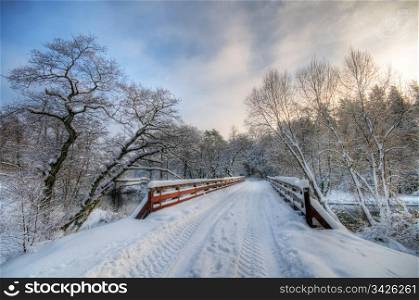 Bridge in winter forest during sunset, lots of snow