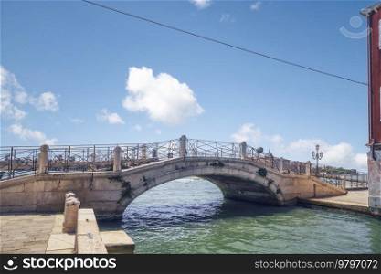 Bridge over a river channel in Venice Italy under a blue sky in the summer