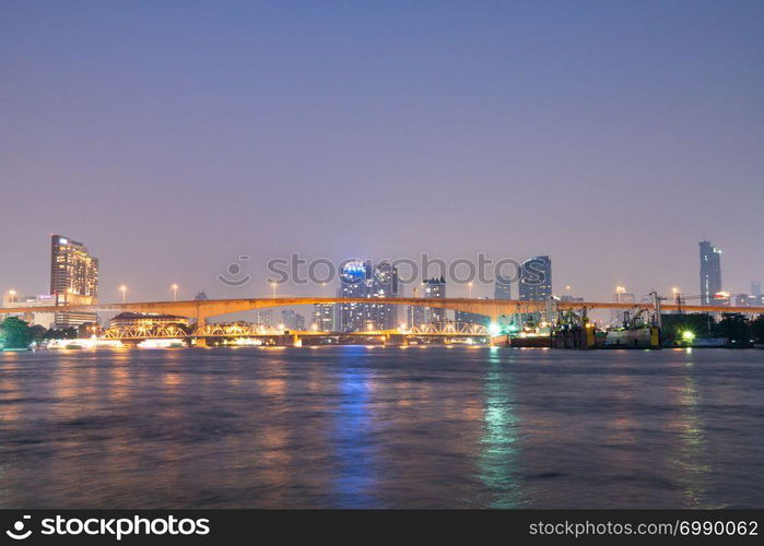 Bridge over river in Bangkok city. Twilight cityscape building and skyscraper in Bangkok city.