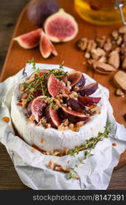 Brie cheese served on a wooden board with figs, walnuts and honey