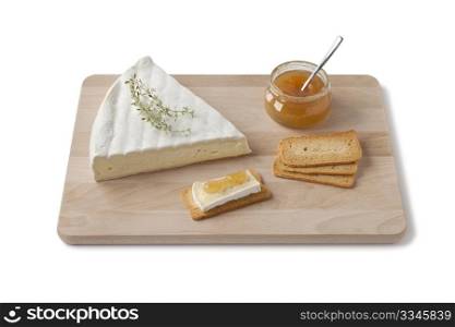 Brie cheese with thyme, toast and fruit sauce as a dessert on a wooden board on white background