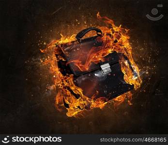 Briefcase burning in fire. Black briefcase in fire flames on dark background