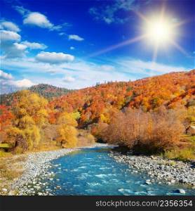Bright autumn landscape of mountain river valley with bright sun.