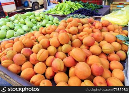 Bright background of fresh fruits, apricots, pears, plums lie in trays in the market and attract attention.. Apricots, pears, peppers, plums are on the market counter for sale.