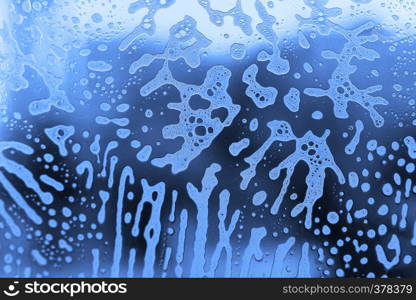 Bright blue abstract texture with soap foam pattern on glass