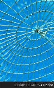 Bright blue sky seen through a modern architecture round or spiral window.