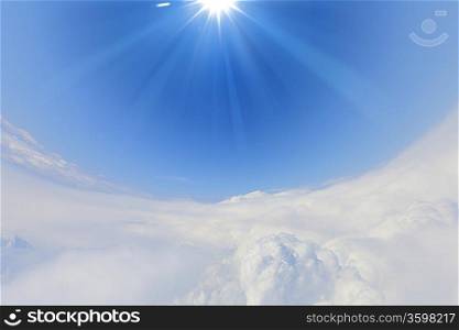 bright blue sky with sun shining and some clouds